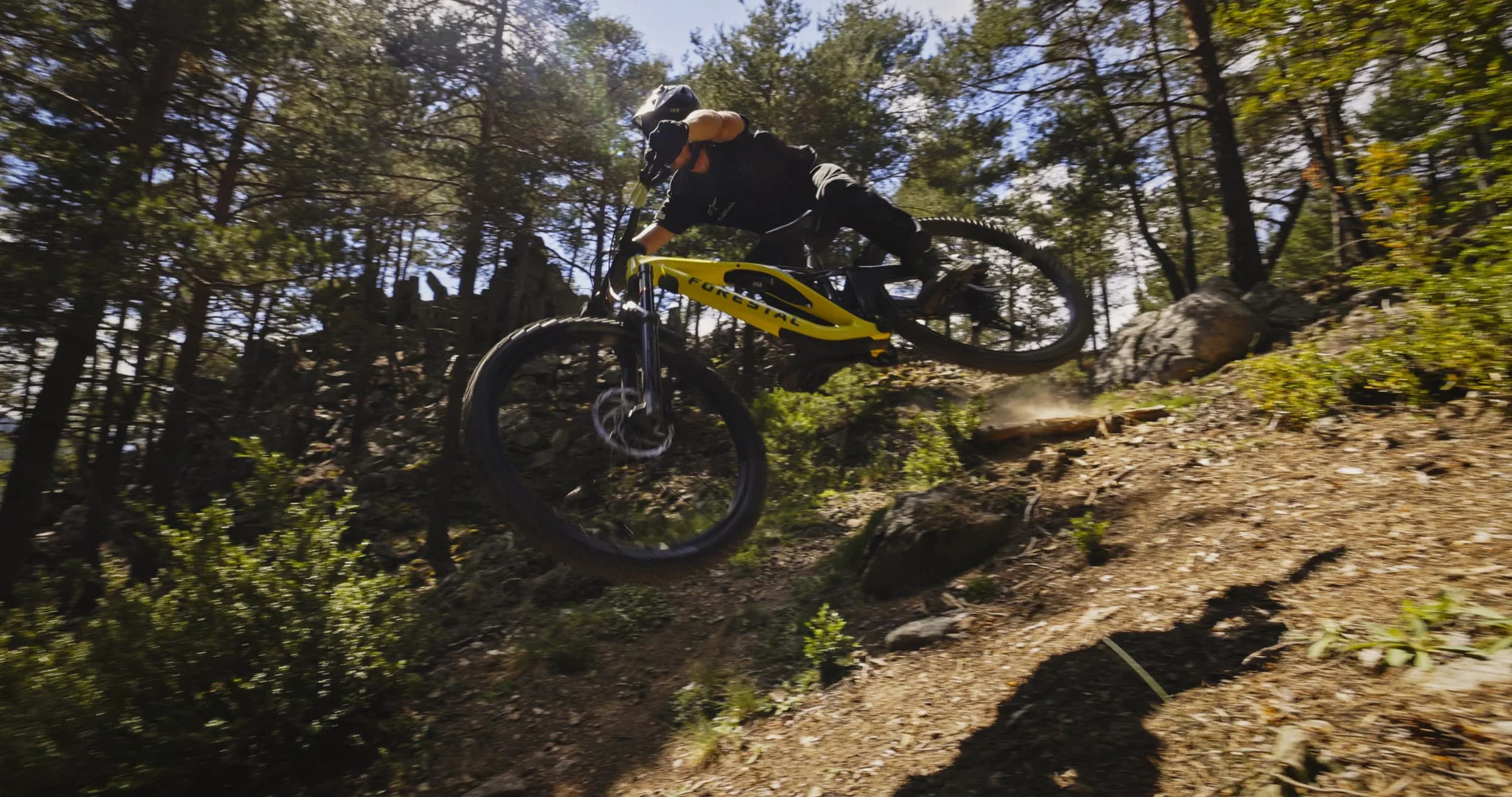 A rider jumps a Forestal Siryon on a forest trail